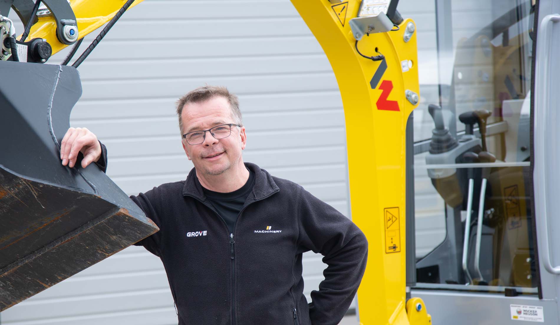 Juha Ojala minikaivinkoneen kauhan alla